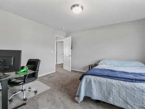 Carpeted bedroom with an office area and baseboards