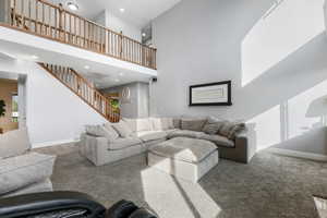 Carpeted living room with a towering ceiling, recessed lighting, stairway, and baseboards