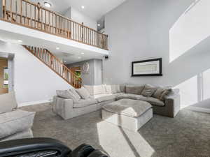 Carpeted living room with a towering ceiling, recessed lighting, stairway, and baseboards