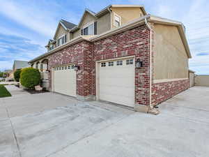 View of home's exterior with concrete driveway, a gate, stucco siding, brick siding, and fence