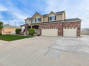 View of front facade with covered porch, driveway, a front yard, an attached garage, and stucco siding