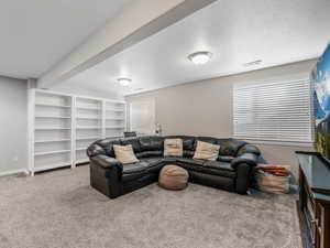 Living room featuring carpet flooring, baseboards, beam ceiling, recessed lighting, and a textured ceiling