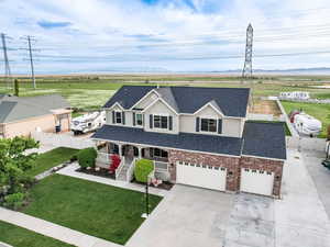 View of front of property with covered porch, concrete driveway, a shingled roof, brick siding, and stucco siding