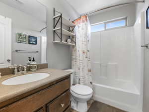 Bathroom featuring toilet, shower / bathtub combination with curtain, and vanity
