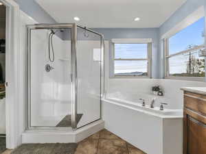 Bathroom with a stall shower, a garden tub, vanity, tile patterned floors, and recessed lighting