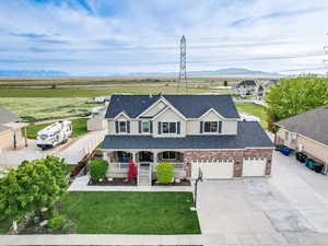 View of front facade featuring covered porch, concrete driveway, a shingled roof, a mountain view, and an attached garage