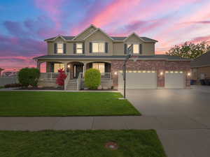 Traditional-style home featuring concrete driveway, a porch, a lawn, brick siding, and an attached garage