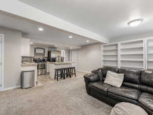 Living area with light colored carpet, recessed lighting, baseboards, and a textured ceiling