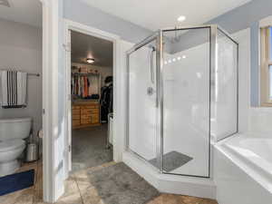 Bathroom featuring a stall shower, a bath, toilet, and a walk in closet