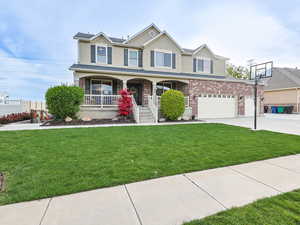 View of front facade with a porch, stucco siding, a front lawn, concrete driveway, and an attached garage