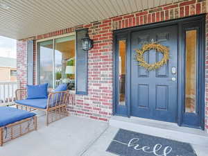Entrance to property with brick siding and covered porch