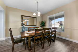 Dining area with a chandelier, wood finished floors, and baseboards