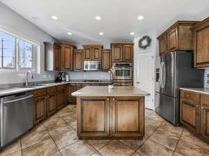 Kitchen with stainless steel appliances, a sink, a kitchen island, recessed lighting, and light countertops