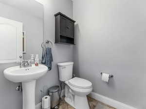 Half bath with baseboards, toilet, and a sink