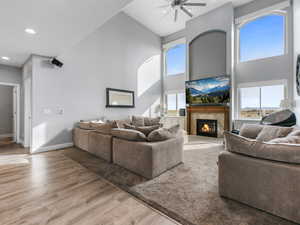 Living area featuring high vaulted ceiling, ceiling fan, wood finished floors, a premium fireplace, and baseboards