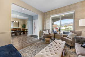 Living area with wallpapered walls, wood finished floors, baseboards, and a chandelier