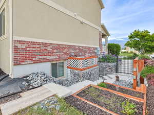 View of side of property featuring a garden, brick siding, and stucco siding