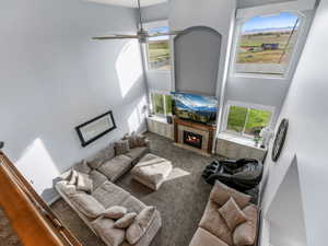 Carpeted living area featuring a high ceiling, ceiling fan, and a high end fireplace
