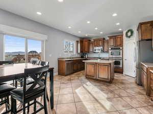 Kitchen featuring stainless steel appliances, recessed lighting, a sink, light countertops, and a center island