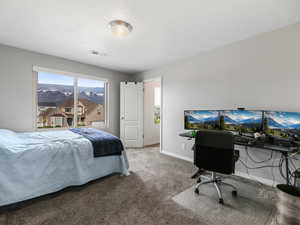 Carpeted bedroom with baseboards and a desk