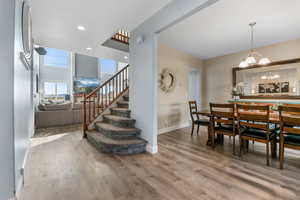 Dining area with wood finished floors, stairs, a chandelier, and baseboards