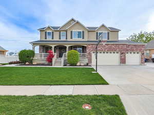 View of front of home featuring driveway, a porch, stucco siding, brick siding, and a garage