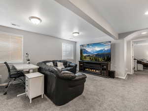 Carpeted living room featuring baseboards and a glass covered fireplace