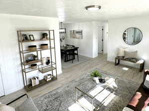 Living area featuring wood finished floors, a textured ceiling, and baseboards