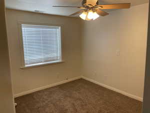 Unfurnished room with dark carpet, a ceiling fan, and baseboards