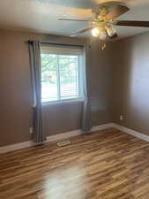 Unfurnished room featuring a ceiling fan, wood finished floors, a textured ceiling, and baseboards