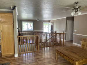Interior space featuring an upstairs landing, a textured ceiling, wood finished floors, and ornamental molding