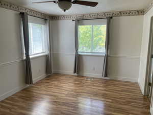 Unfurnished bedroom with a textured ceiling, wood finished floors, baseboards, and a ceiling fan