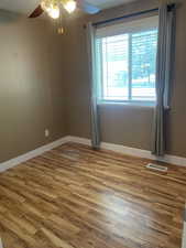 Spare room featuring ceiling fan, baseboards, and wood finished floors