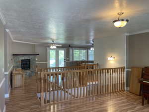 Living area featuring wood finished floors, a textured ceiling, a ceiling fan, baseboards, and a fireplace