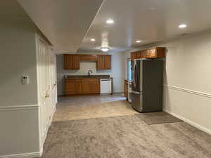 Kitchen featuring freestanding refrigerator, white dishwasher, light carpet, recessed lighting, and a sink