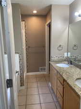 Full bathroom featuring tile patterned flooring, double vanity, and a textured ceiling
