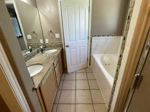 Full bathroom featuring a whirlpool tub, tile patterned flooring, and double vanity