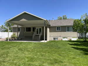 Back of property with stucco siding, entry steps, a patio, and roof with shingles