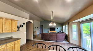 Living area featuring arched walkways, vaulted ceiling, baseboards, ceiling fan, and dark stone finish floors