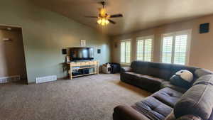 Carpeted living area with lofted ceiling, a ceiling fan, and baseboards