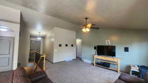 Carpeted living room featuring ceiling fan, baseboards, vaulted ceiling, and arched walkways