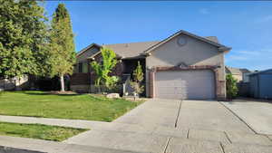 View of front of property featuring a front lawn, an attached garage, driveway, brick siding, and stucco siding
