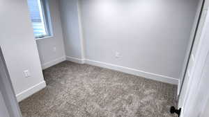 Spare room featuring carpet flooring and baseboards