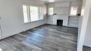 Unfurnished living room with wood finished floors, ornamental molding, baseboards, and a fireplace