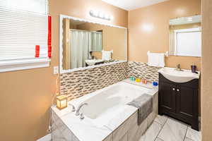 Master bath with a jetted tub, vanity, marble finish flooring, and a shower with curtain