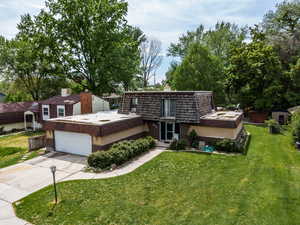 Front of property with mansard roof, a front lawn, concrete driveway, and a chimney