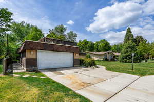 View of front facade featuring brick siding, a front lawn, mansard roof, and driveway
