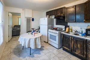 Second Kitchen with white appliances, light marble finish flooring, a sink, under cabinet range hood, and a heating unit