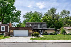 Front of property with mansard roof, a garage, concrete driveway, and brick siding