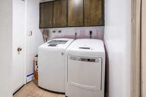 Laundry room with cabinet space, separate washer and dryer, and light tile  finished floors